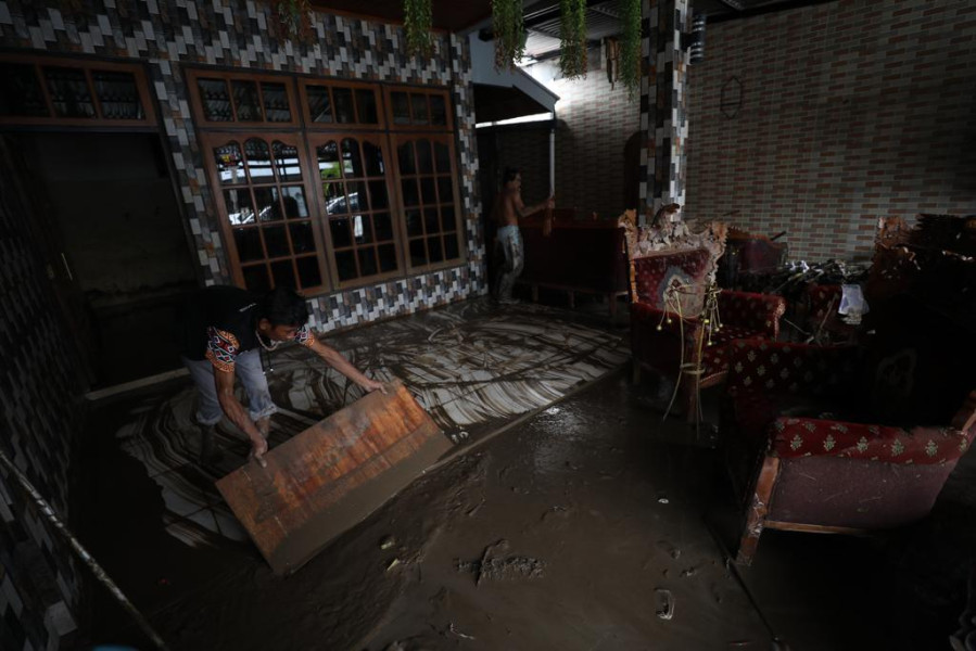Warga membersihkan lumpur sisa banjir dari dalam rumahnya di Jalan Raya Bailang, Lingkungan 1, Kelurahan Bailang, Kecamatan Bunaken, Kota Manado, Sulawesi Utara, Sabtu (28/1).