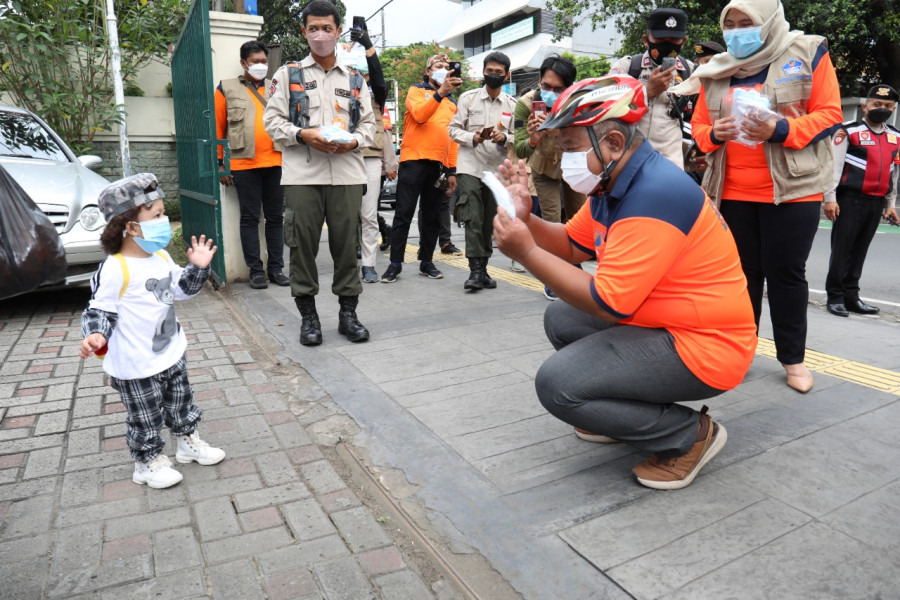 Sekretaris Utama BNPB Lilik Kurniawan (kanan) memberikan masker kepada seorang anak di Gondangdia, Jakarta Pusat, Jumat (11/2).