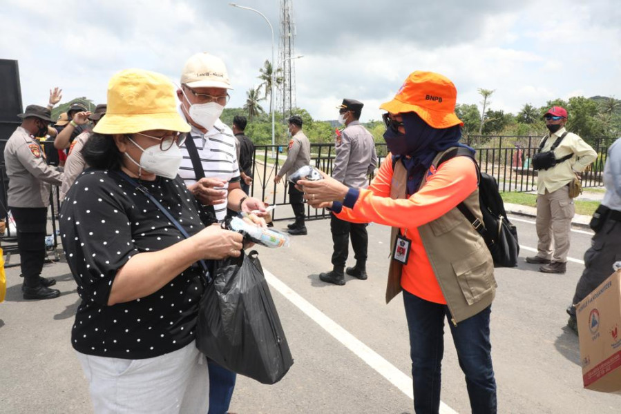 Direktur Pemulihan dan Peningkatan Sosial-Ekonomi Sumber Daya Alam BNPB Andi Eviana (kanan) membagikan paket protokol kesehatan (prokes) di Gate 3 Pertamina Mandalika International Street Circuit, Lombok Tengah, Nusa Tenggara Barat, Minggu (20/3).