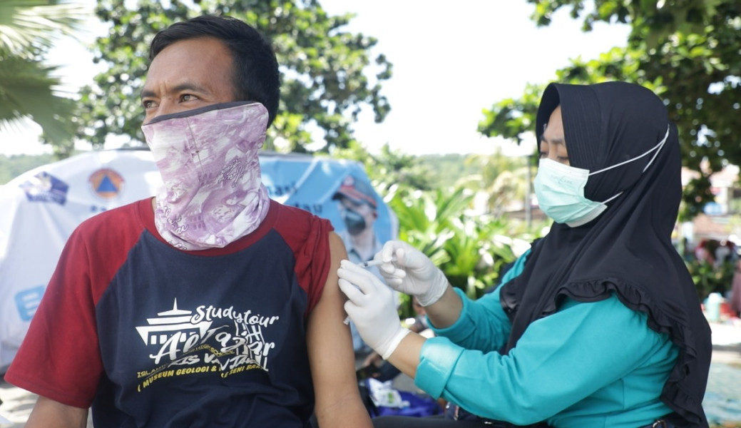 Salah satu wisatawan melakukan vaksinasi di gerai vaksinasi yang berada di kawasan Pantai Kuta Mandalika, Nusa Tenggara Barat, Minggu (13/3).
