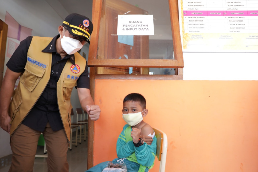 Kepala BNPB sekaligus Ketua Satgas Penanganan Covid-19 Letjen TNI Suharyanto (kiri) mengajak seorang siswa melakukan salam komando usai disuntik vaksin Covid-19 di SD 009 Sei Beduk, Kota Batam, Kepulauan Riau, Kamis (24/3).