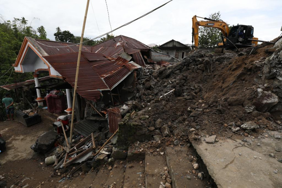 Alat berat jenis eskavator membersihkan puing material longsoran yang menimpa sebuah rumah warga di Kelurahan Singkil 2, Lingkungan 3, Kecamatan Singkil, Kota Manado, Sulawesi Utara, Sabtu (28/1).