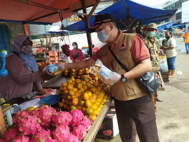 Penyerahan bantuan masker BNPB kepada masyarakat di Pasar Cipulir, Kebayoran Lama, Jakarta Selatan, Jumat (11/2).