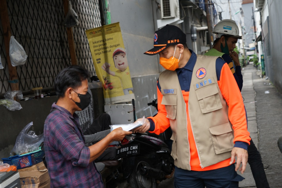 Pembagian 10.000 masker oleh Inspektorat Utama BNPB bersama BPBD Provinsi DKI Jakarta, TNI/Polri dan aparat terkait di wilayah Kelurahan Bendungan Hilir, Jakarta Pusat, Sabtu (12/2).