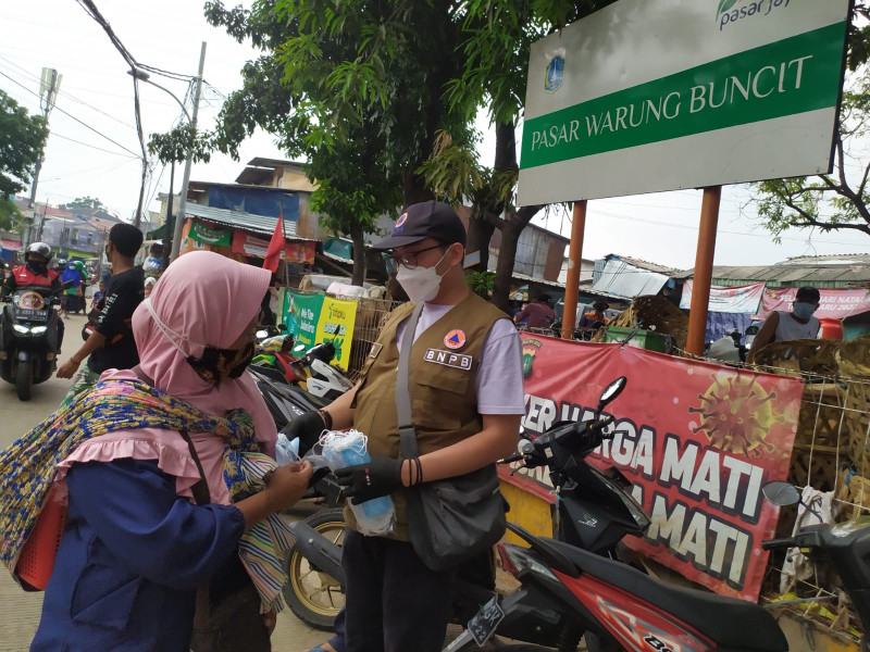 Pembagian masker oleh unit Direktorat Fasilitas Penanganan Korban dan Pengungsi BNPB di Kelurahan Bangka, Jakarta Selatan, Sabtu (12/2).