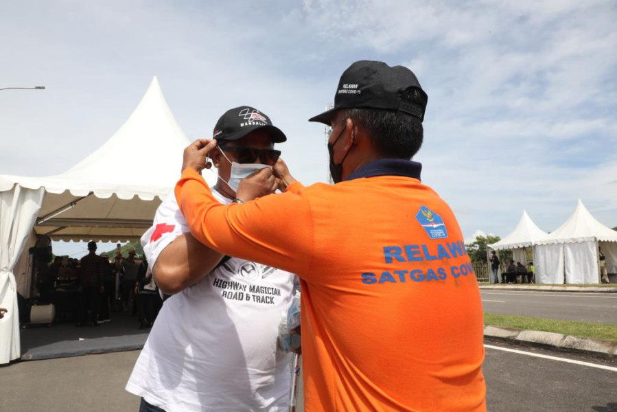 Relawan BPBD membantu salah satu penonton MotoGP Mandalika menggunakan masker medis di Gate 3 Pertamina Mandalika International Street Circuit, Lombok Tengah, Nusa Tenggara Barat, Minggu (20/3).