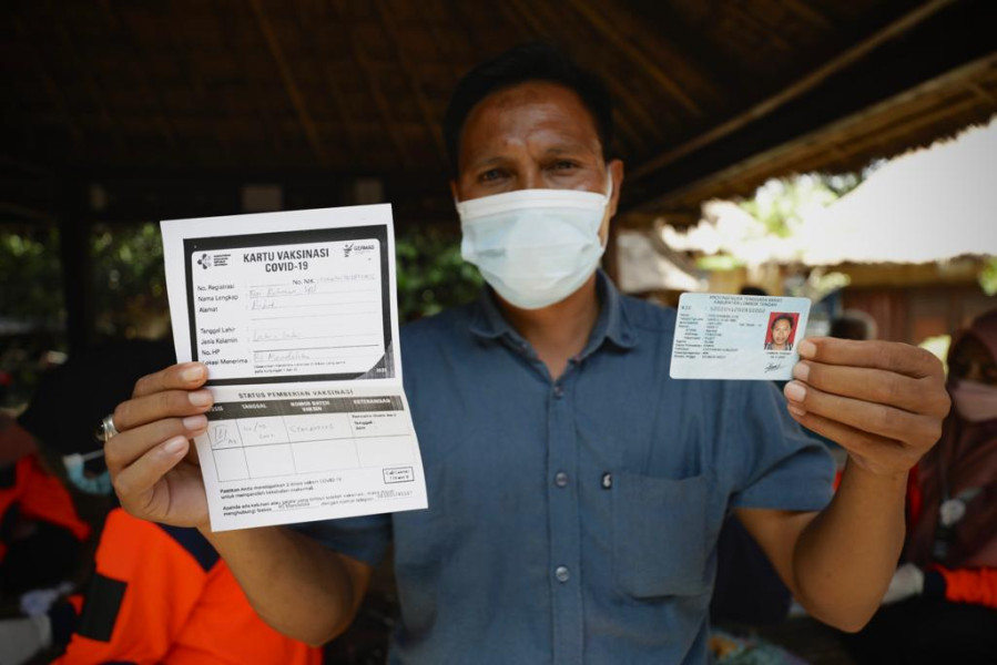 Warga Suku Sasak menunjukkan sertifikat sementara usai mendapatkan vaksinasi lanjutan yang diinisiasi BNPB dan Pemerintah NTB di Desa Adat Sade, Rembitan, Pujut, Lombok Tengah, NTB, Senin (15/3).