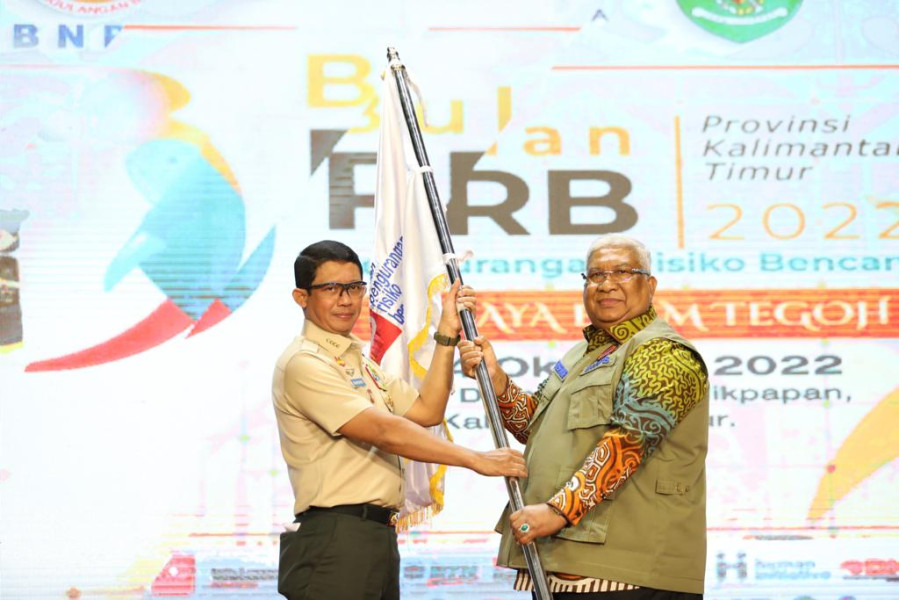 Kepala BNPB Letjen TNI Suharyanto (kiri) memberikan pataka Bulan Pengurangan Risiko Bencana (PRB) kepada Gubernur Provinsi Sulawesi Tenggara sebagai tuan rumah Bulan PRB 2023 di BSCC Dome, Balikpapan, Jumat (14/10).